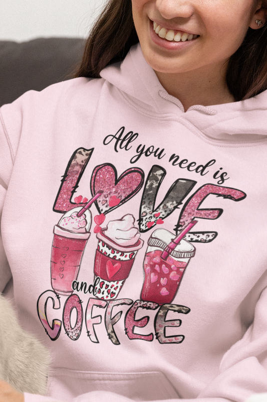 Light Pink hooded graphic sweatshirt with coffee graphic on front.  Three different style of coffees and the words "All You Need is Love and Coffee".  Back of sweatshirt is plain , no graphic. Modeled by woman