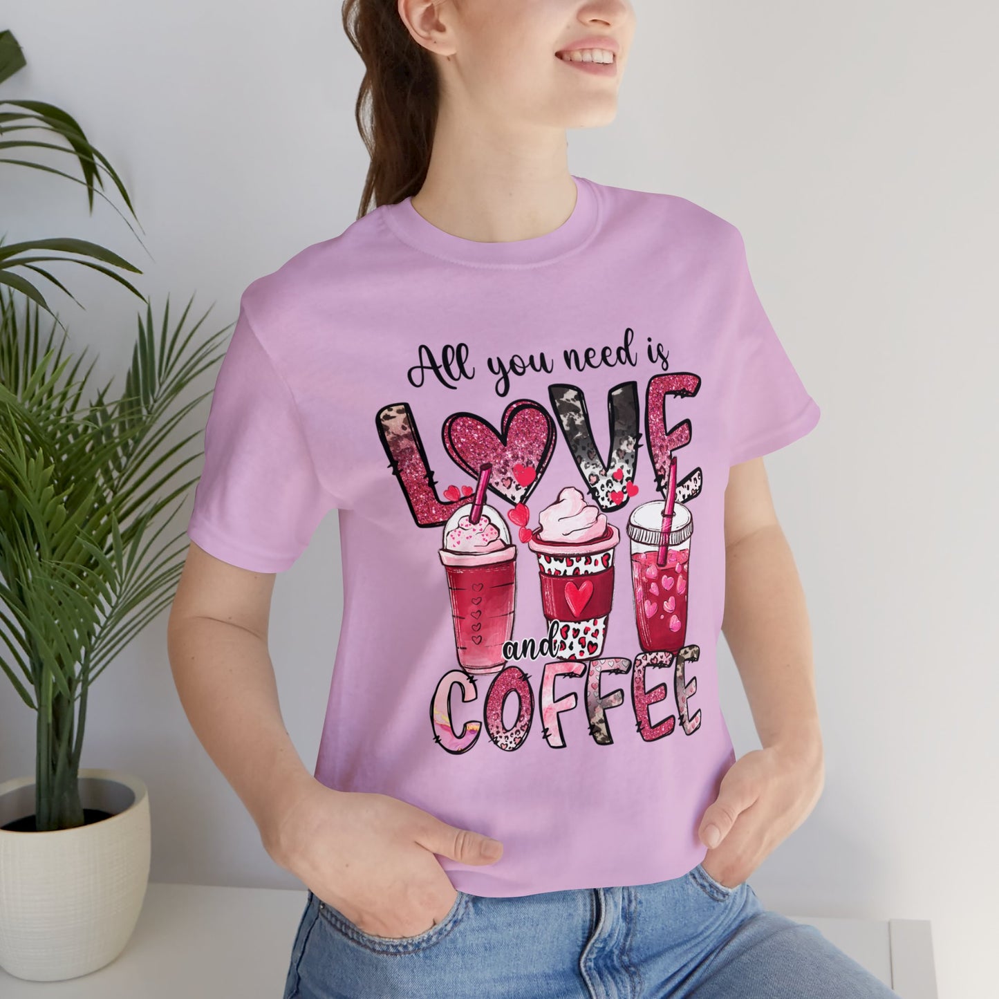 Lilac Colored t-shirt with coffee graphic on front.  Three different style of coffees and the words "All You Need is Love and Coffee".  Back of shirt is plain , no graphic. Modeled by woman