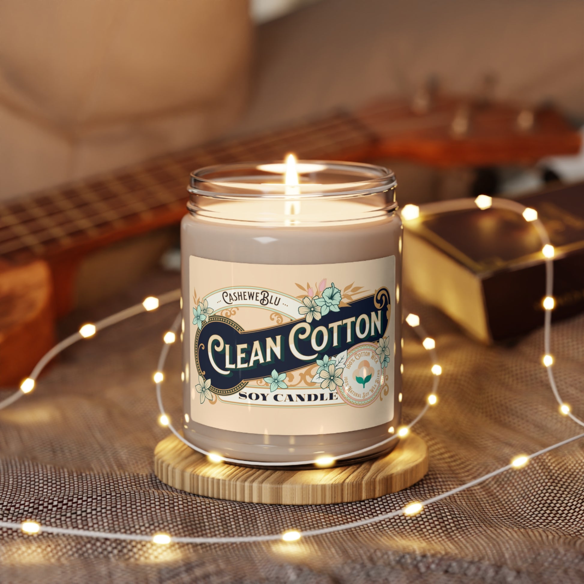 Clean Cotton 9 oz soy candle that is lit and surrounded by pixie lights