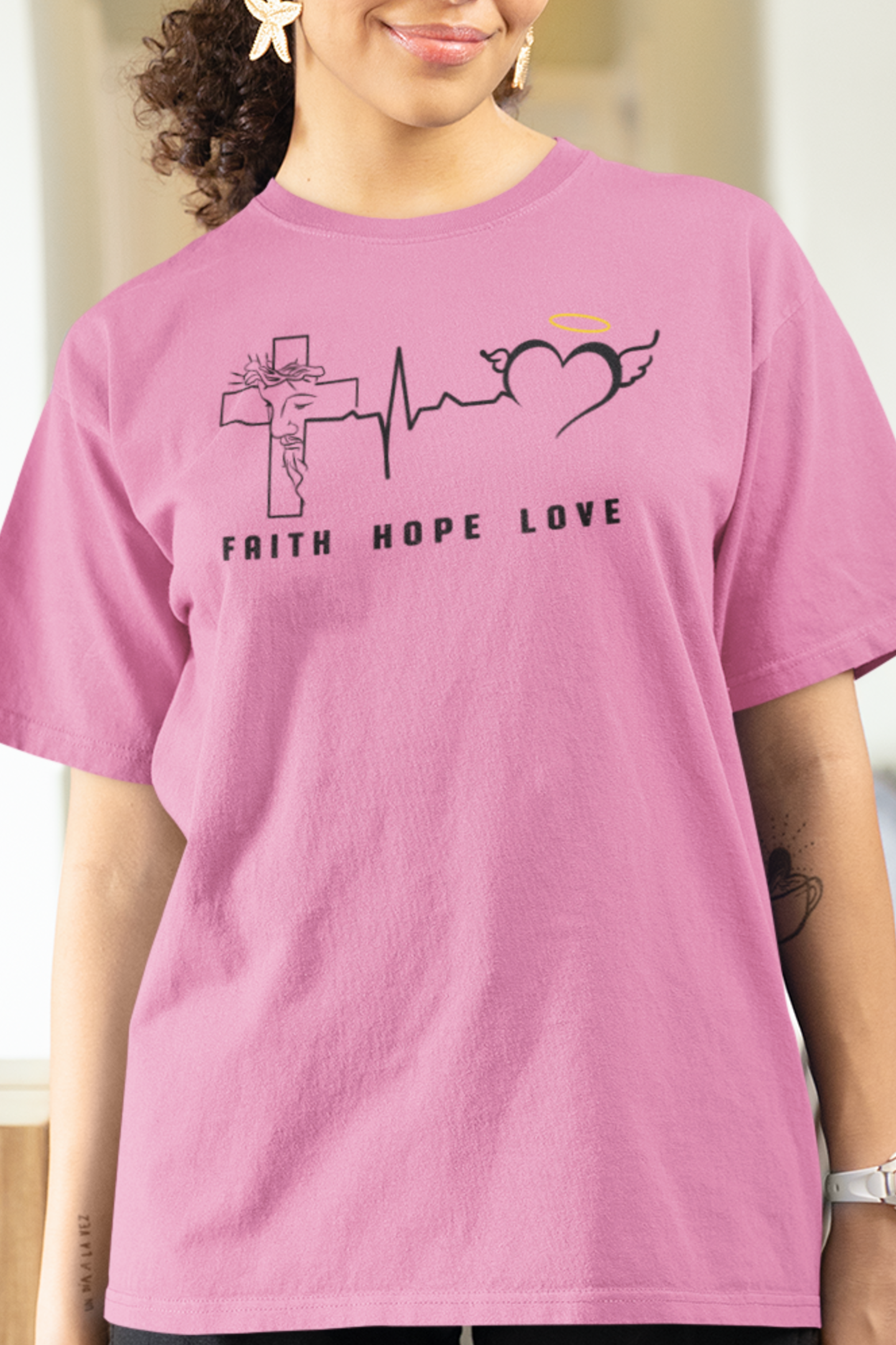 Azalea t-shirt with a heartbeat graphic spanning across the chest in three sections.  The first is a cross with Jesus's face, then the heartbeat symbol that flows into an open heart with wings.  Under each graphic is the words faith hope and love.  Graphic is on the front with a plain back no graphic. Woman model