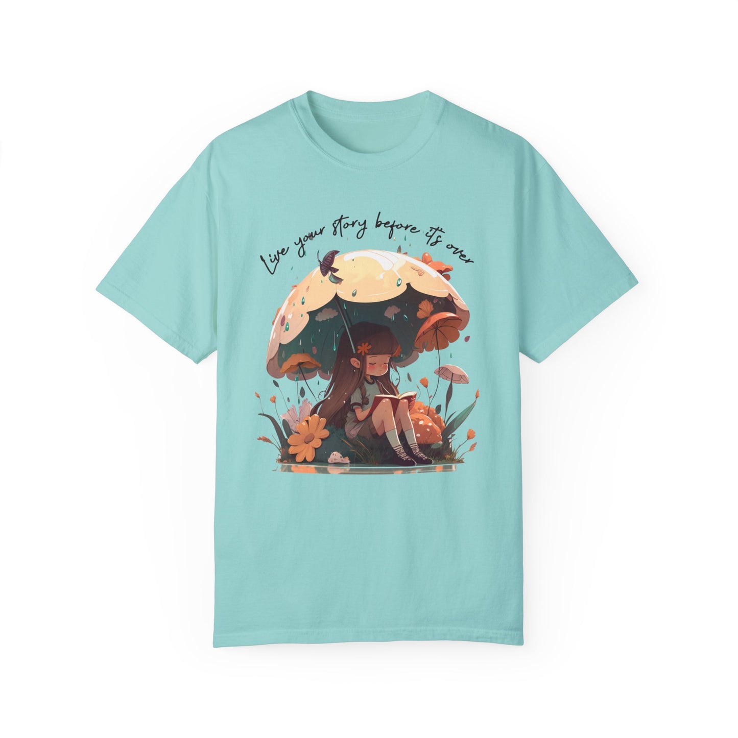 Chalky Mint colored T-Shirt with girl sitting under an umbrella reading a book in the rain surrounded by flowers and mushrooms with the words live your story before it's over arching above the umbrella