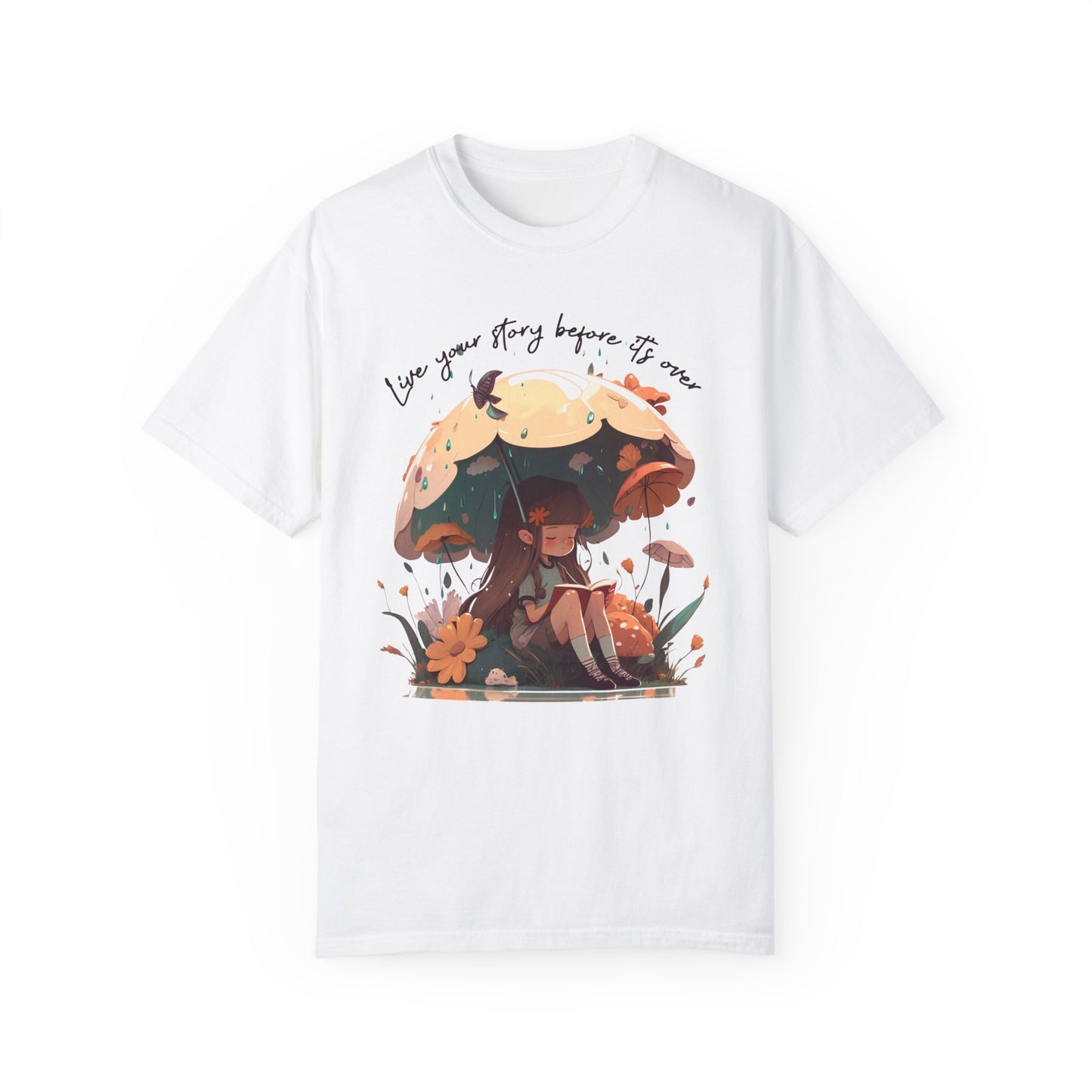 White colored T-Shirt with girl sitting under an umbrella reading a book in the rain surrounded by flowers and mushrooms with the words live your story before it's over arching above the umbrella