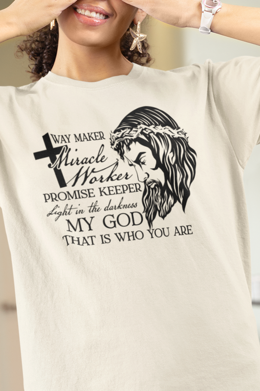 Natural Color Christian graphic t-shirt with Jesus wearing a crown of thorns on one side and the other says "Way Maker Miracle Worker, Promise Keeper, Light in the Darkness, My God That is Who You Are" on the other.  This is a front graphic tee with a plain back.  Modeled by a woman.