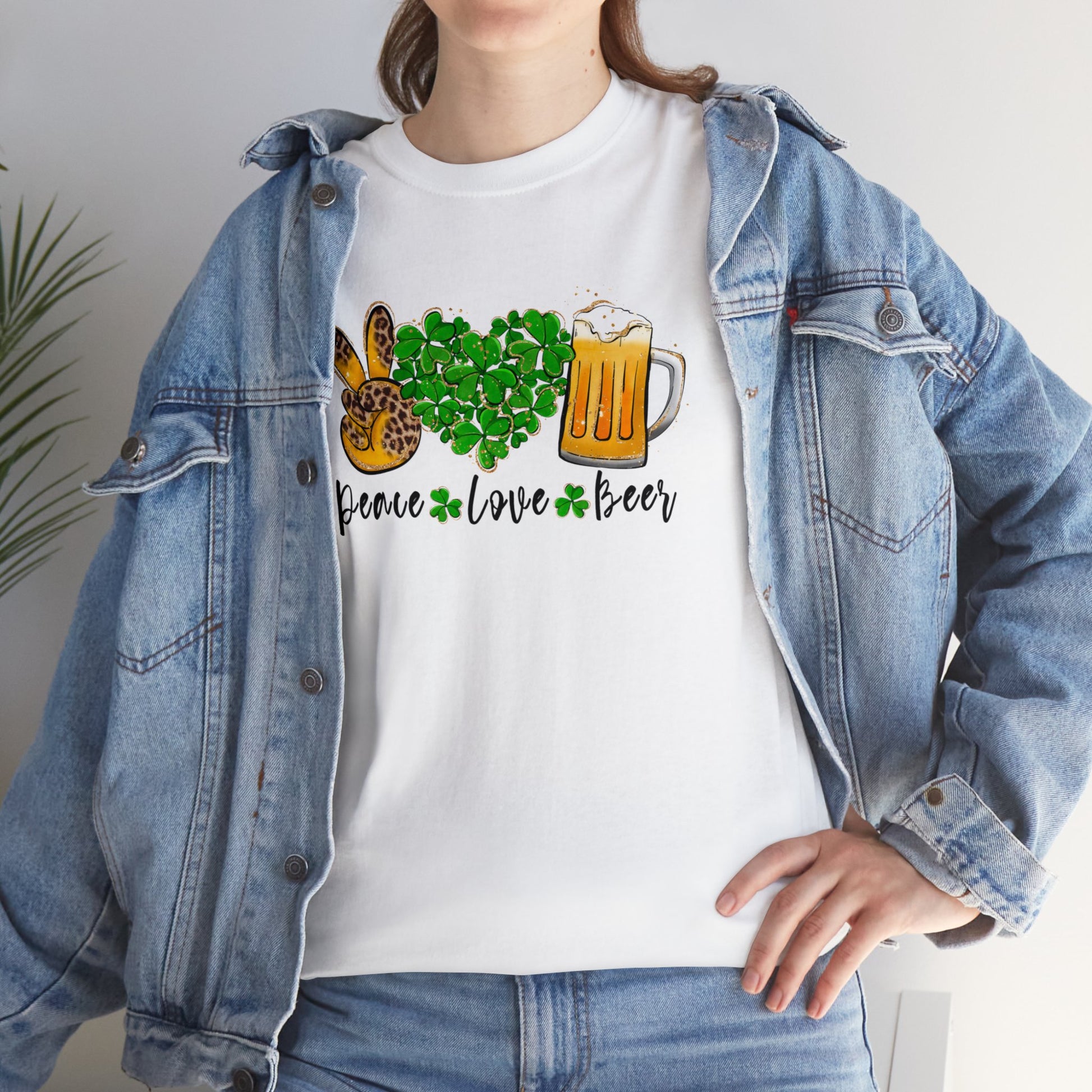 White Color T-Shirt with the words Peace, Love, Beer written on it with a hand in a peace sign and heart filled with shamrocks and a mug of beer above each of the words. Mock up on woman wearing jean jacket.