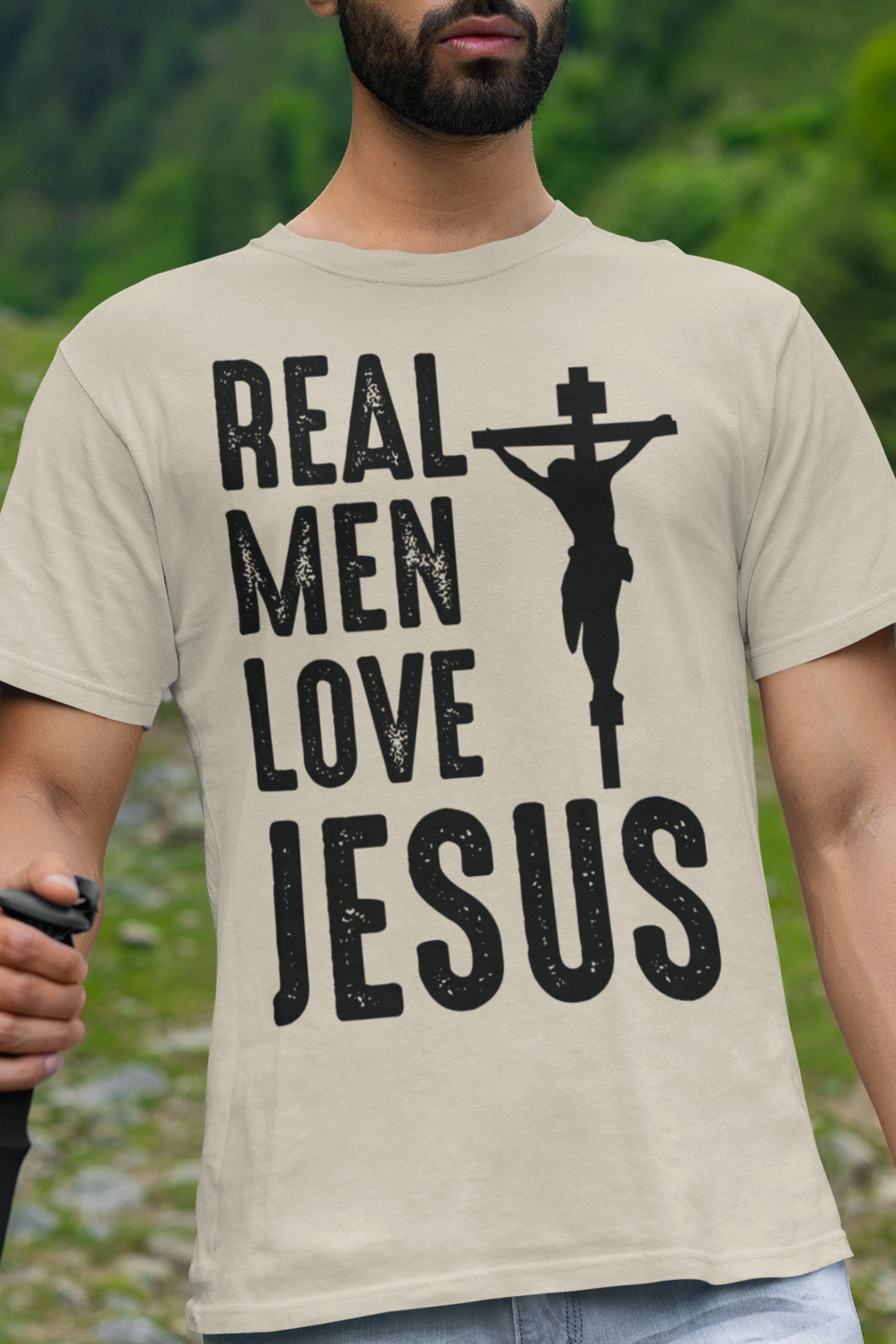 Sand colored t-shirt with the words "Real Men Love Jesus" and a graphic with Jesus on the Cross