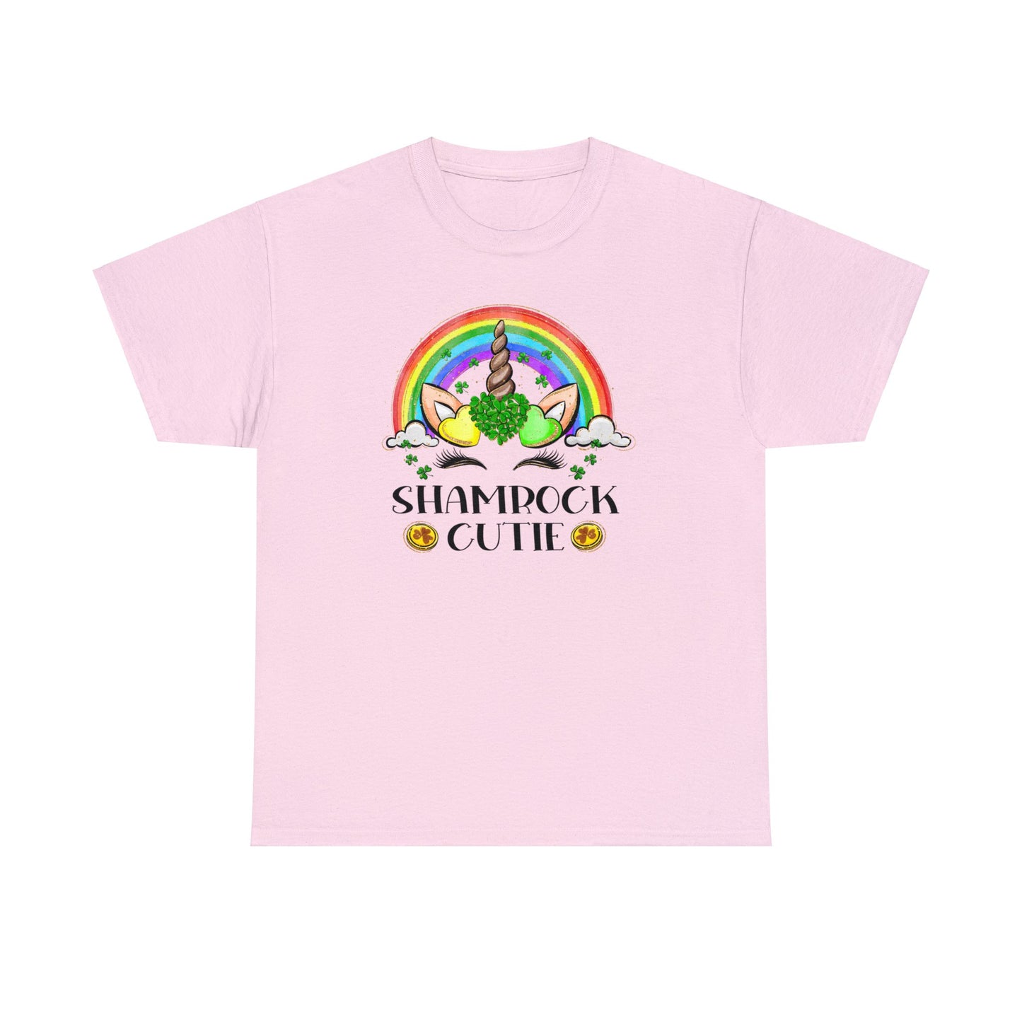 Light pink color St. Patrick's Day T-Shirt with a rainbow surrounding a unicorn with hearts at the base of the horn one made up of shamrocks and the words Shamrock Cutie under the unicorn face.