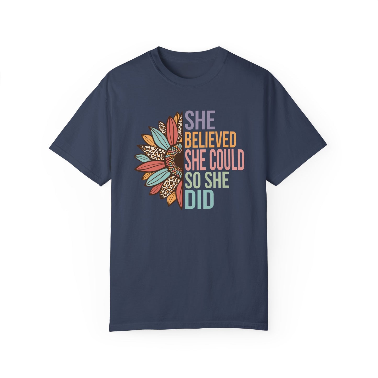 Midnight colored t-shirt with the saying "She Believed She Could So She Did" as half of the sunflower and a retro design other half of the flower with petals of leopard print, teal, rust and golden yellow