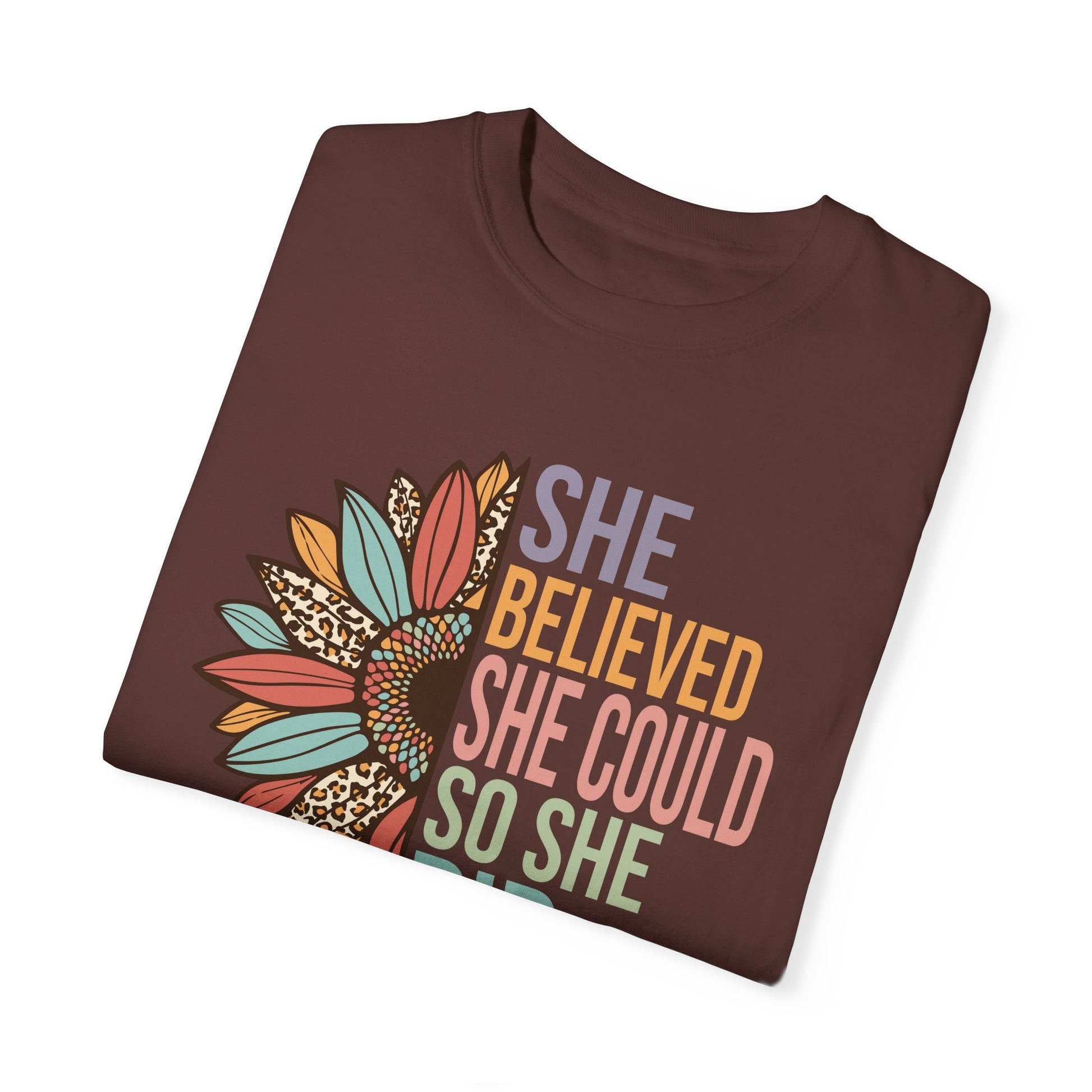 Vineyard colored t-shirt with the saying "She Believed She Could So She Did" as half of the sunflower and a retro design other half of the flower with petals of leopard print, teal, rust and golden yellow